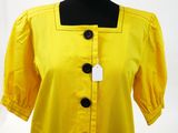the back of a yellow blouse with black buttons on a mannequin dummy