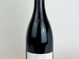 the bottle of red wine is sitting on a white surface