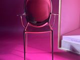 a red chair sitting in front of a mirror on a pink floor