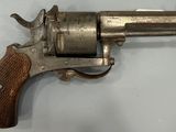 gros plan d'un revolver avec une poignée en bois sur une surface blanche
