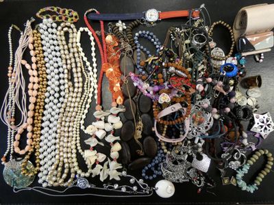 many different necklaces and bracelets laid out on a table