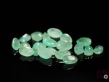 a close up of a bunch of green stones on a black surface
