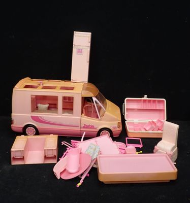 un petit bus rose avec un lit et d'autres objets