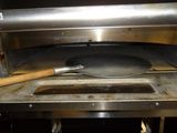 a pizza oven with a pizza in it and a spatula in front of it
