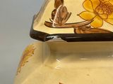 a yellow vase with flowers painted on it sitting on a table