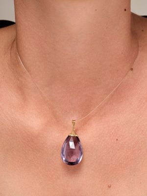 un gros plan d'une femme portant un collier orné d'une pierre violette