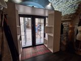 une grande porte ouverte donnant sur une pièce où se trouve un tapis à carreaux