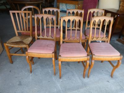 quatre chaises en bois avec des coussins rembourrés roses et une chaise en osier