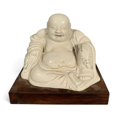 statue of a laughing buddha sitting on a wooden base