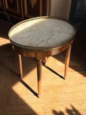 une petite table au plateau en marbre posée sur un parquet en bois massif