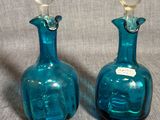une paire de bouteilles en verre bleues avec des bouchons transparents, sur fond gris