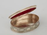an old silver box with a red lid sitting on a white surface