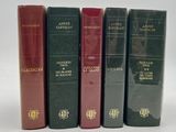 four books are lined up in a row on a white surface