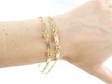 someone is wearing a gold bracelet and a gold chain bracelet