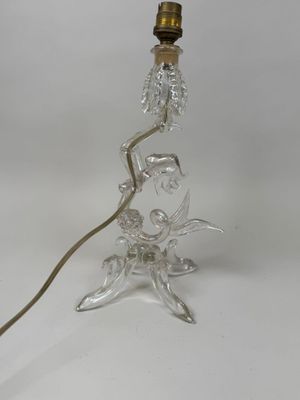 une lampe de table en verre transparent surmontée d'un abat-jour doré