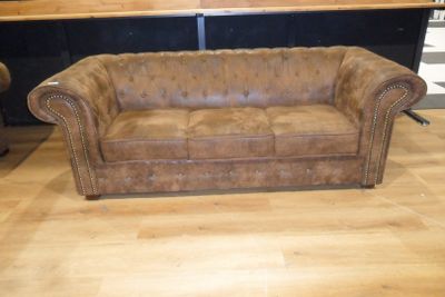 a brown leather couch sitting on a hard wood floor