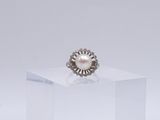 une image représentant une bague ornée d'une perle et d'un diamant posée sur un cube transparent
