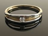 un gros plan d'une bague en or et en argent posée sur une surface noire