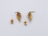two gold earrings and a gold earring on a white surface