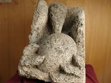 a stone sculpture of a rabbit on a red cloth
