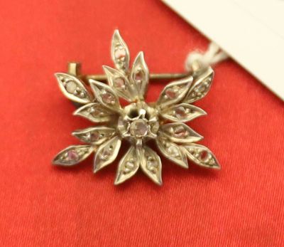 une petite broche en forme de fleur en argent posée sur un tissu rouge