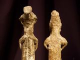 two stone figurines of a man and a woman on a table