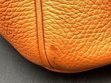 an orange leather purse sitting on top of a black table
