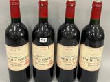 four bottles of wine are lined up on a white surface