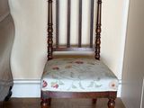 une chaise en bois dont l'assise est recouverte d'un tissu à motifs floraux, placée dans un coin de la pièce