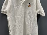un polo blanc avec un écusson de Mickey Mouse sur la poitrine
