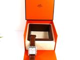 an orange box with a watch inside of it on a white surface