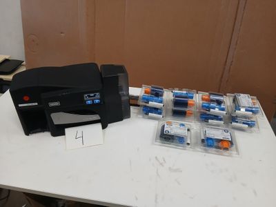 une petite imprimante posée sur une table, à côté d'un tas de piles