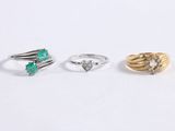 three different rings, one with a green stone and one with a diamond