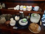 many plates and bowls on a wooden shelf in a room