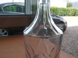 une bouteille en verre posée sur une table avec une voiture en arrière-plan