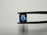 quelqu'un tient une pince dans laquelle est sertie un diamant bleu