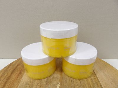 trois pots de peinture jaune et blanche posés sur une planche à découper en bois