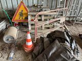 une clôture sur laquelle est accrochée une pancarte de chantier, à côté d'un tas d'ordures
