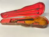 un vieil étui à violon contenant un violon, posé sur une surface blanche