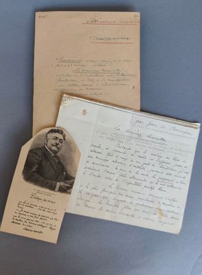 une vieille photo d'un homme en costume-cravate, assis à côté d'une feuille de papier sur laquelle sont inscrits des mots