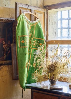un gilet vert accroché au mur, à côté d'un vase de fleurs