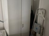a white refrigerator in the corner of a room next to a ladder