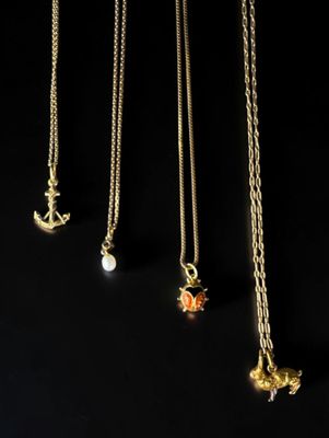 quatre colliers en or ornés de breloques différentes sur fond noir