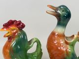 two ceramic ducks sitting next to each other on a table