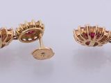 a pair of gold and ruby earrings on a white surface