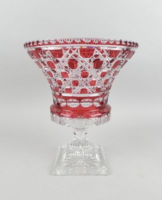 une image représentant un bol en verre rouge posé sur un socle transparent
