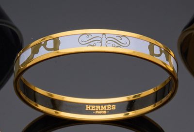 two gold and white bang bracelets with the word hermess on them