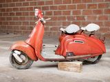 a red scooter that is parked in front of a brick wall