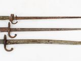 three old iron swords are displayed on a white surface