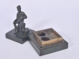 a statue of a man sitting on a chair next to a box